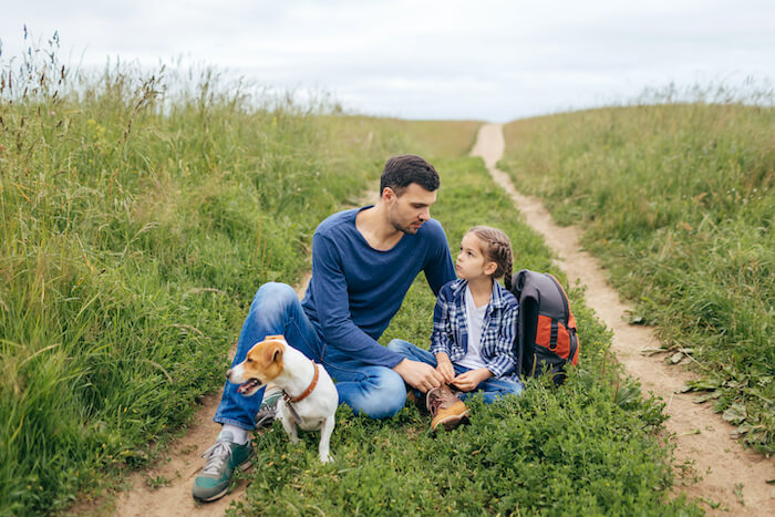 father and daughter outside with a dog